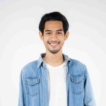 Handsome young photographer poses with smiles and holding professional digital camera in the studio.